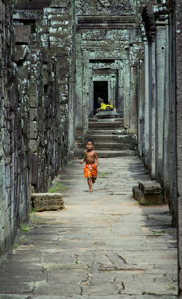 A boy runs through the ruins at Angkor Wat, Cambodia. 2006
